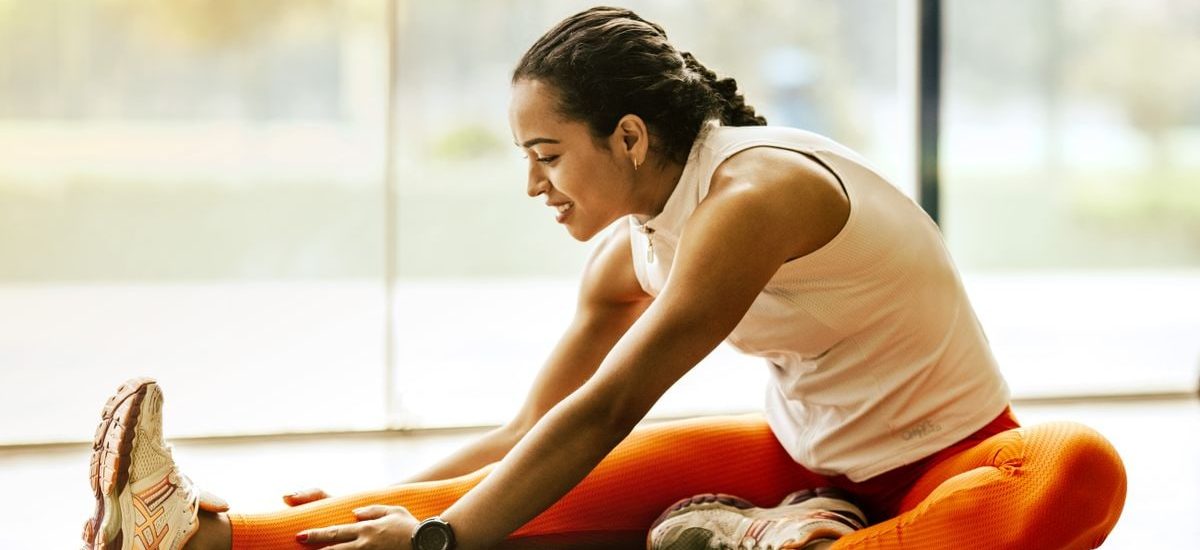 A woman enjoying a yoga stretch indoors, promoting a healthy lifestyle.